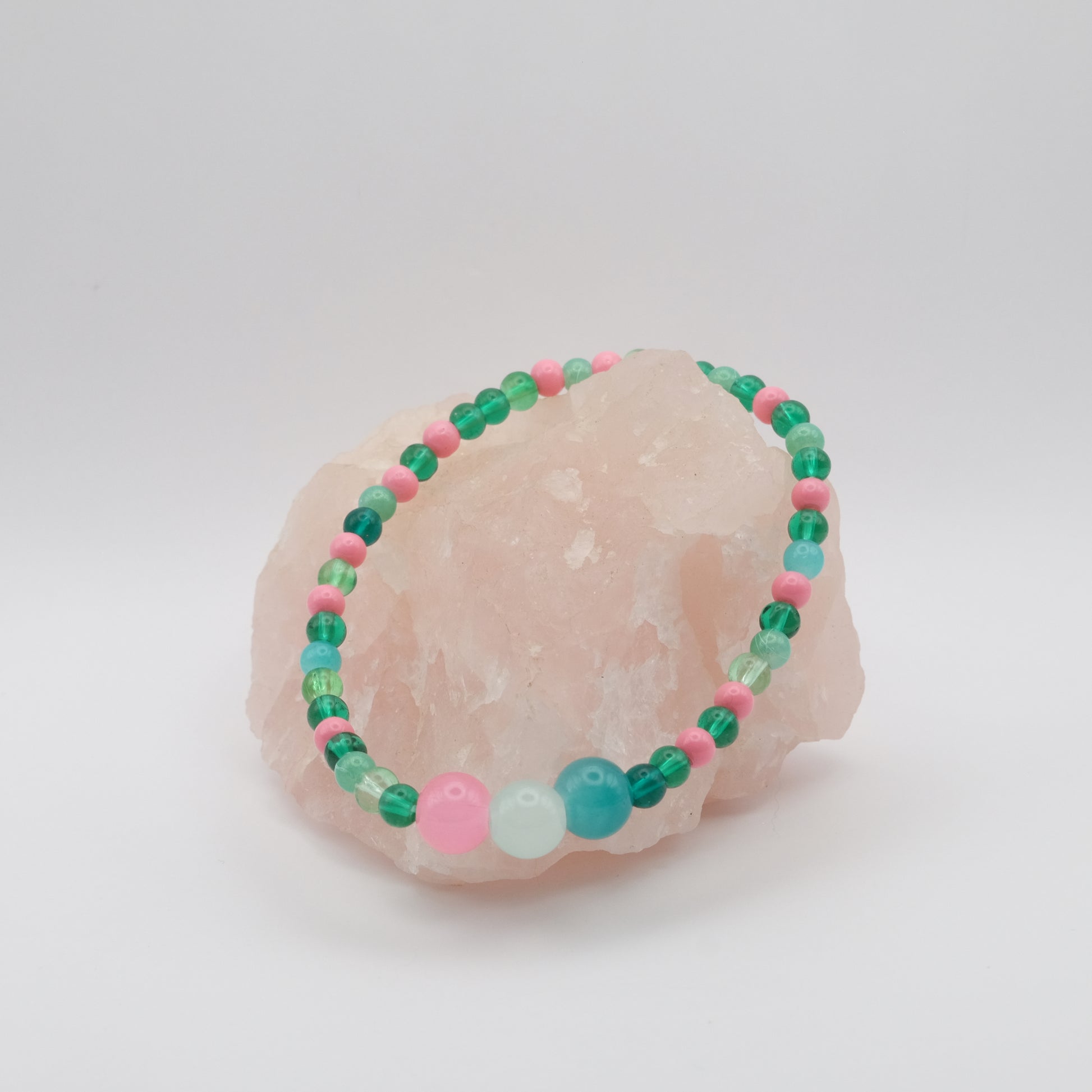 Beaded bracelet with green, pink, and blue beads on a white background