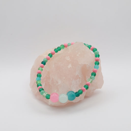 Beaded bracelet with green, pink, and blue beads on a white background