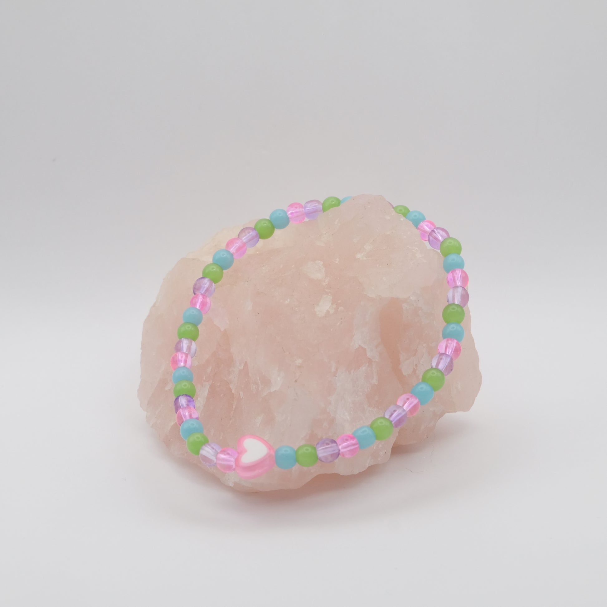 Pastel beaded bracelet on a seashell against a light gray background