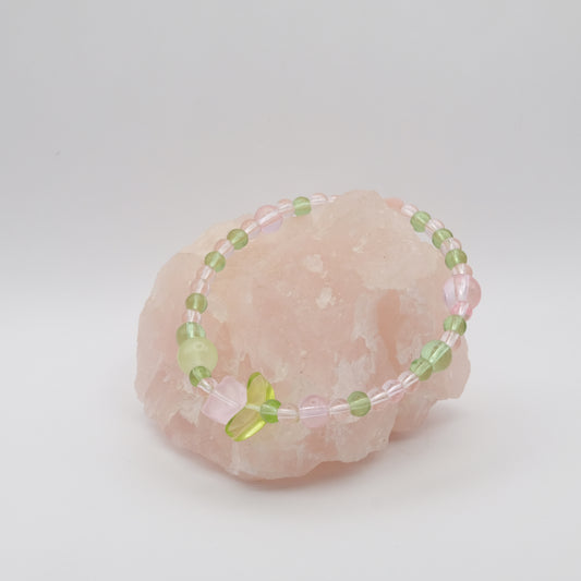 Beaded bracelet with green and pink beads on a pink stone against a white background