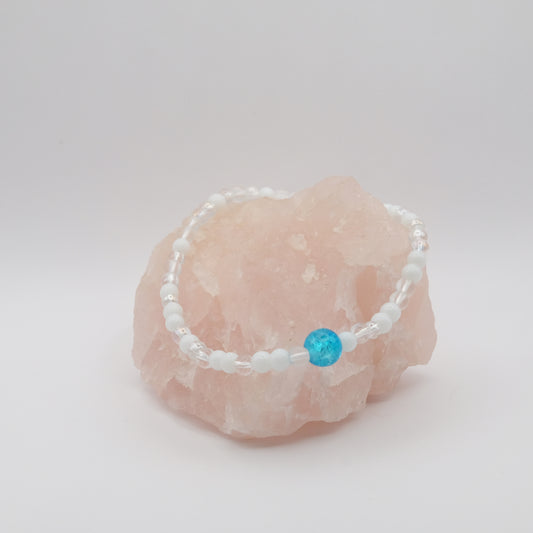 Beaded bracelet with a blue bead on a pink stone against a white background