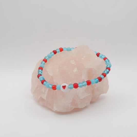 Beaded bracelet with red and blue beads on a pink stone