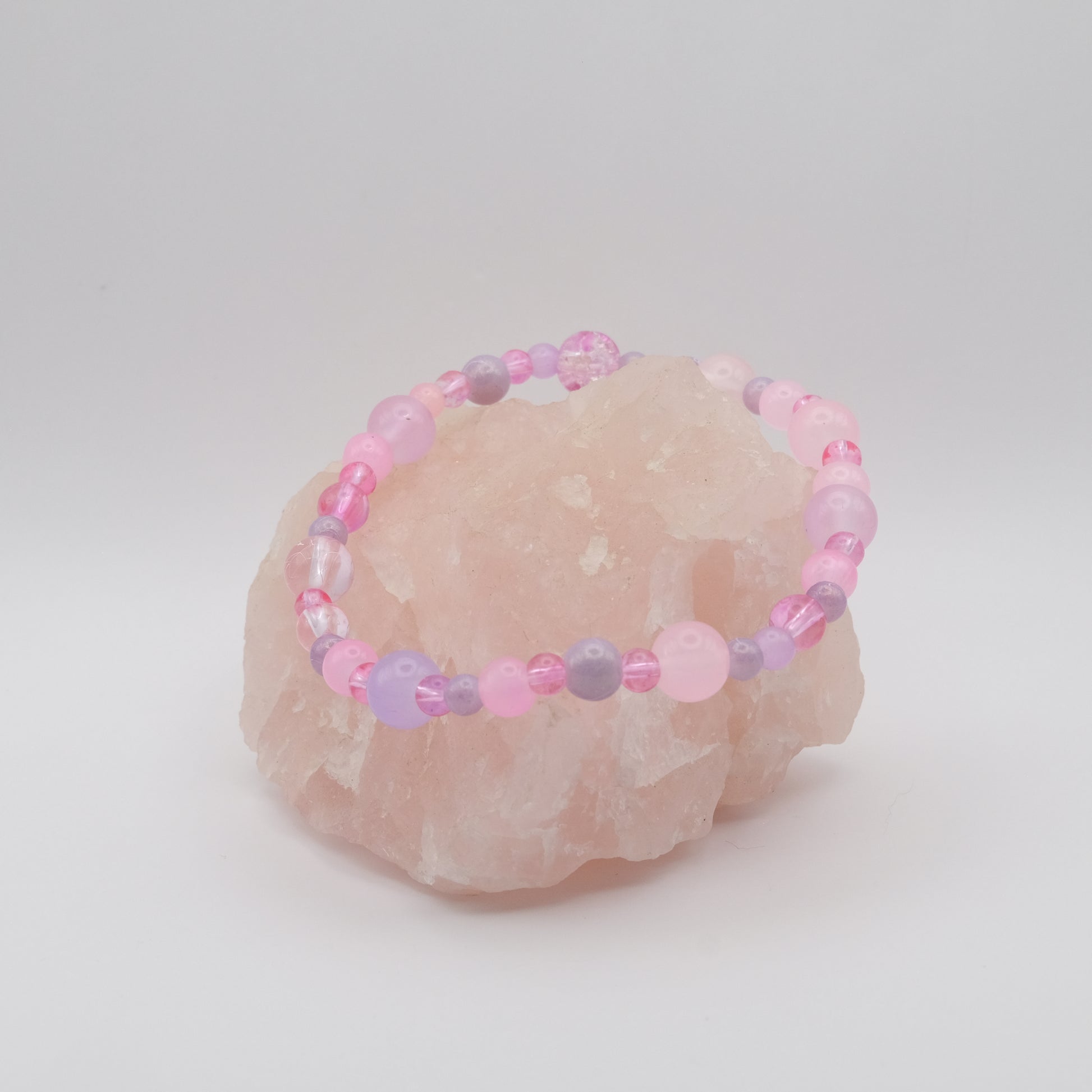 Beaded bracelet with pink and purple beads on a stone surface