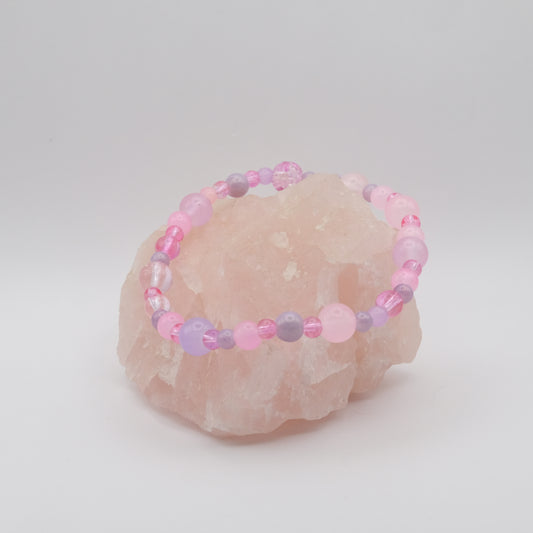 Beaded bracelet with pink and purple beads on a stone surface