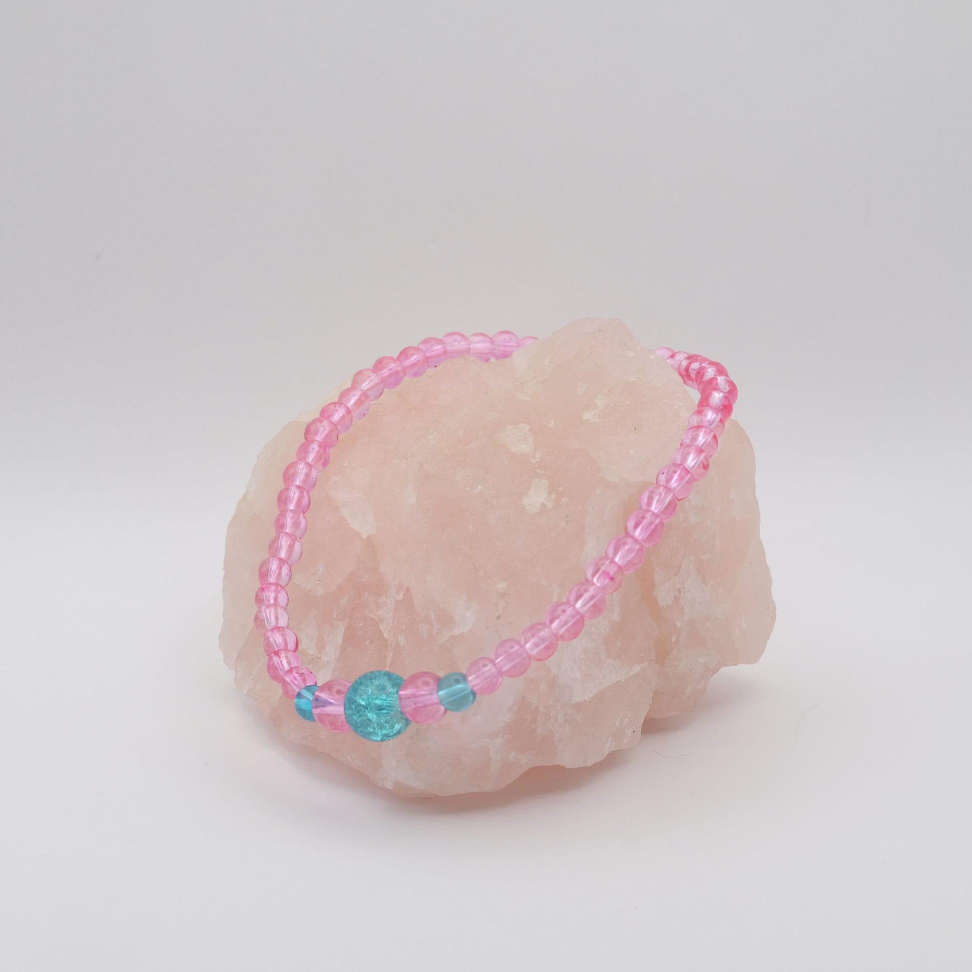 Pink beaded bracelet with a blue bead on a pink stone