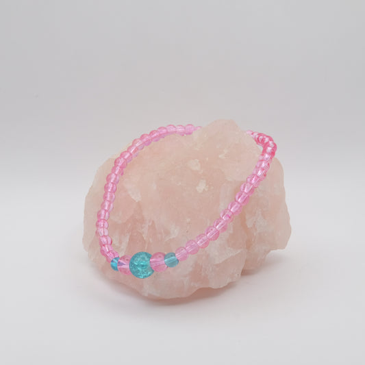 Pink beaded bracelet with a blue bead on a pink stone