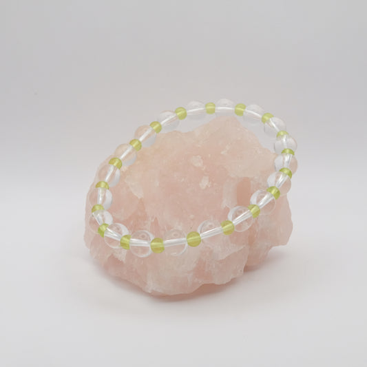 Beaded bracelet with clear and green beads on a pink crystal background