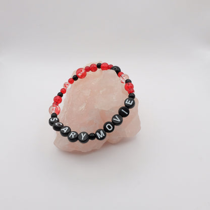 Bracelet with 'SCARY MOVIE' beads on a pink stone with a white background