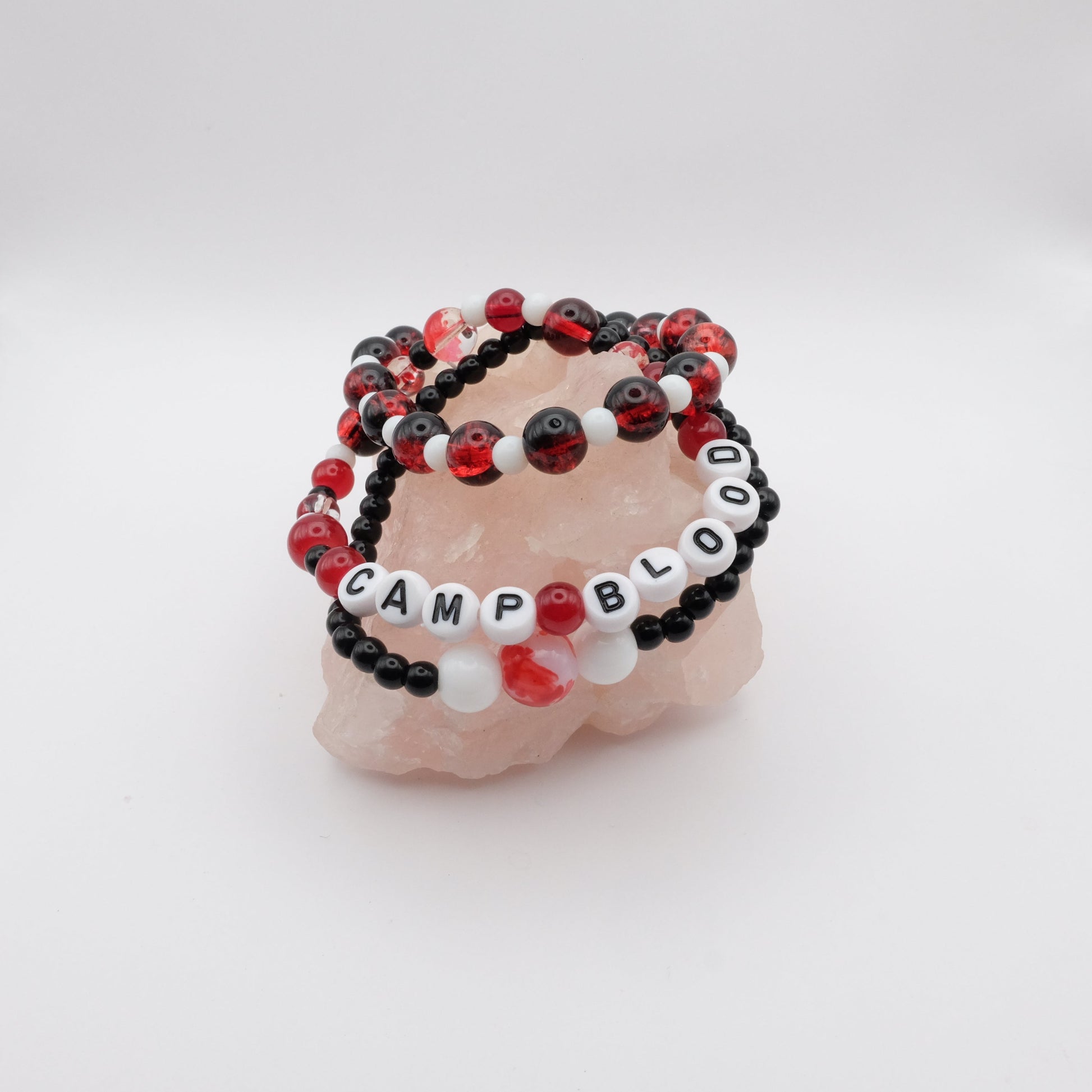 Set of black and red beaded bracelets with 'CAMP BLOOD' on a white background