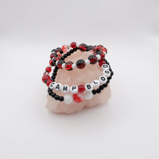 Set of black and red beaded bracelets with 'CAMP BLOOD' on a white background