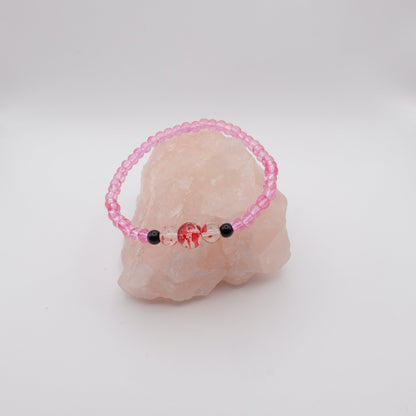 Pink beaded bracelet with black beads on a pink stone against a white background