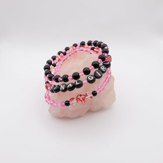 Set of pink and black beaded bracelets on a white surface