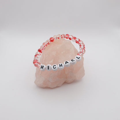 Bracelet with 'MICHAEL' beads on a pink stone with a white background