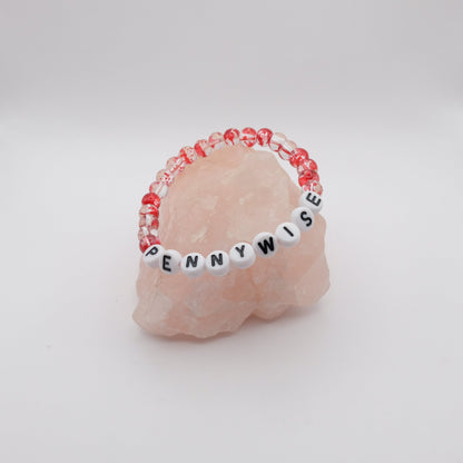 Pink stone with a beaded band labeled 'PENNYWISE' on a white background
