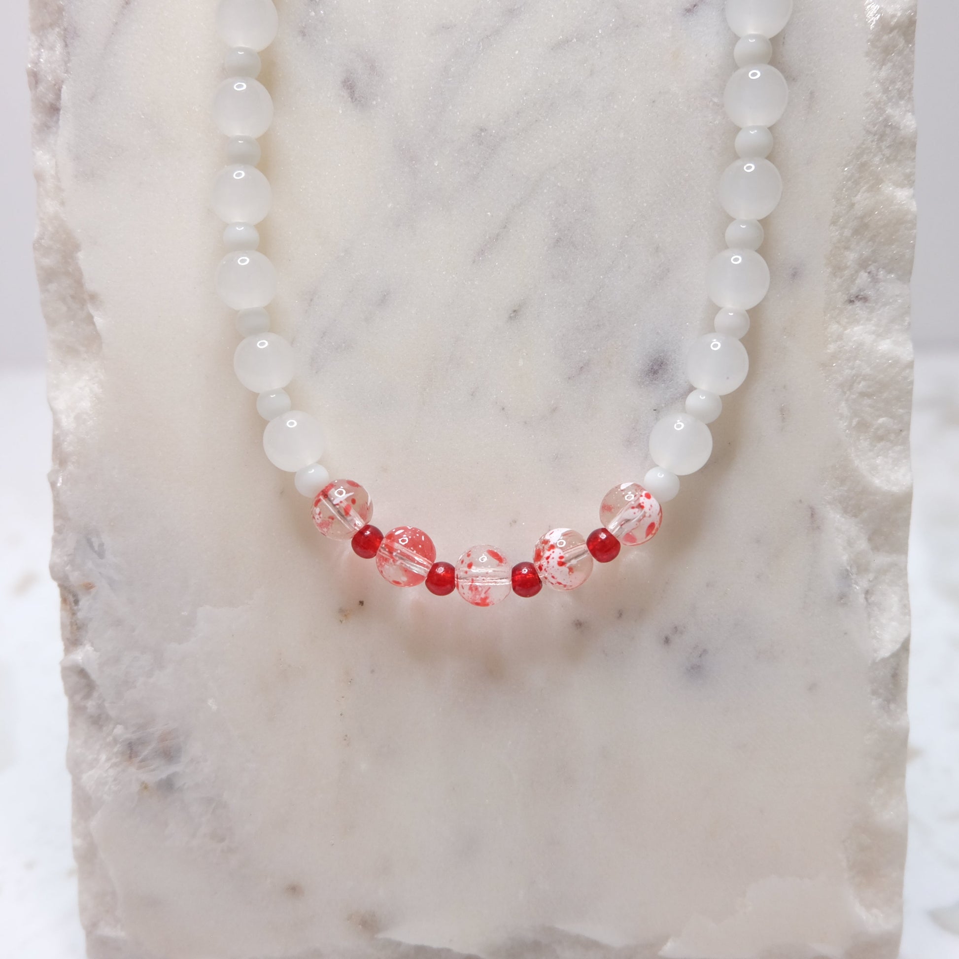 Necklace with red and white beads on a textured surface