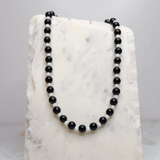 Black beaded necklace on a white marble surface