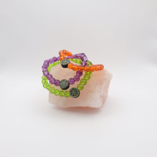 Set of colorful beaded bracelets on a piece of pink stone with a white background