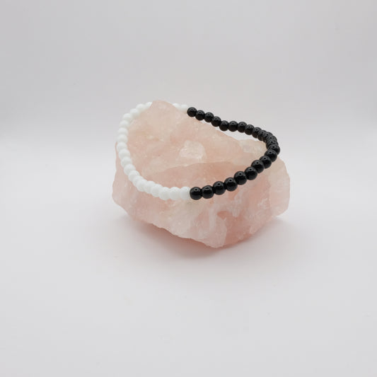 Black and white beaded bracelet on a pink crystal with a white background