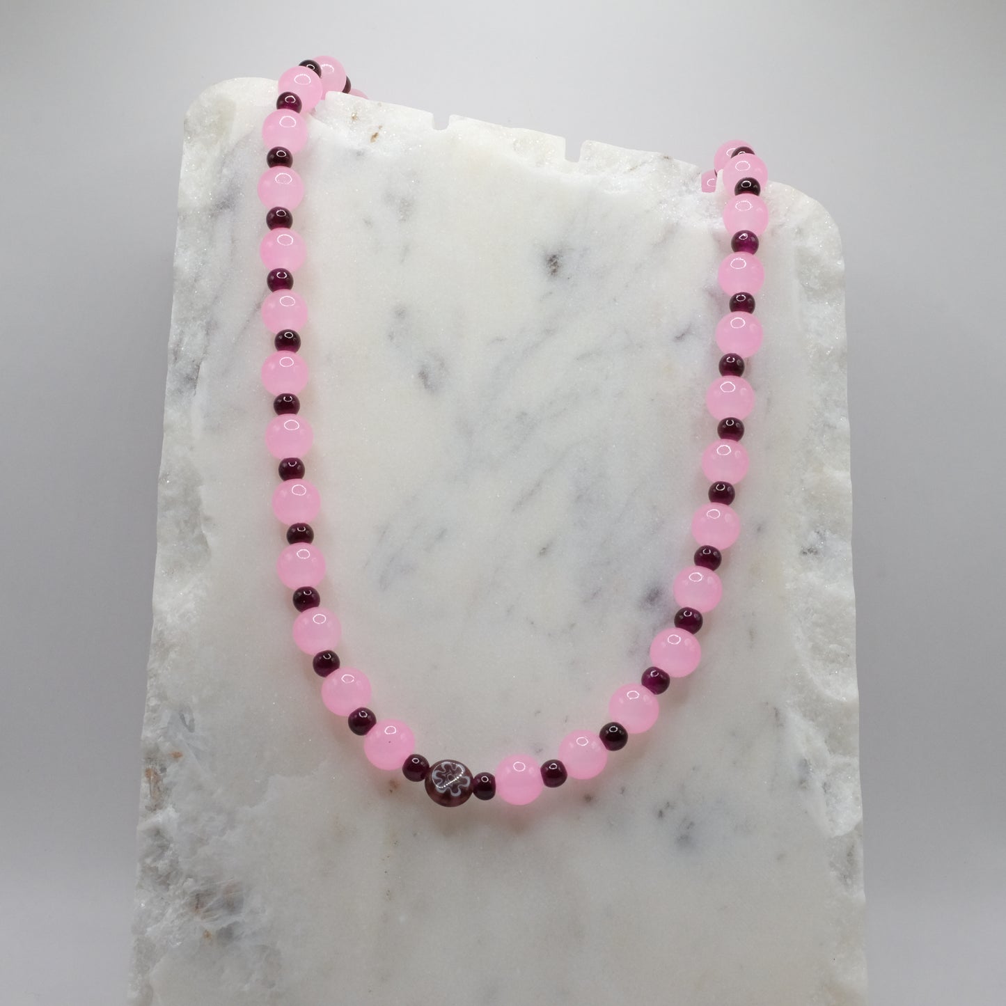 Necklace with pink and dark beads on a marble surface