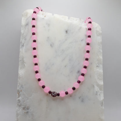 Necklace with pink and dark beads on a marble surface