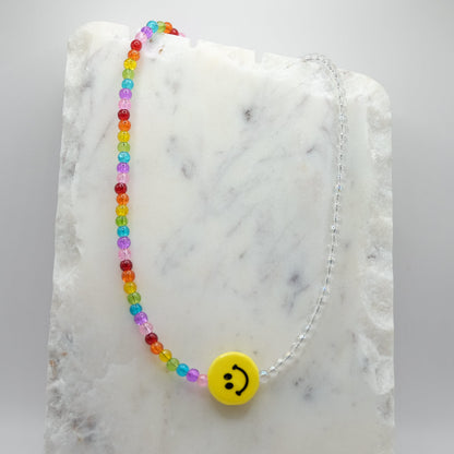 Colorful beaded necklace with a smiley face charm on a marble surface