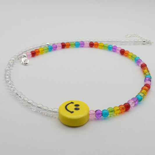 Colorful beaded bracelet with a yellow smiley face charm on a light gray background