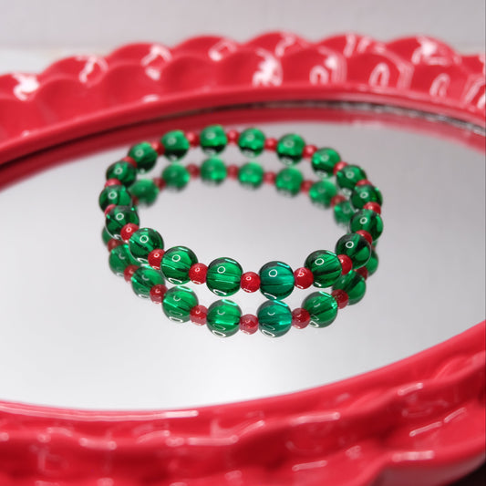 Green and red beaded bracelets on a red mirror.