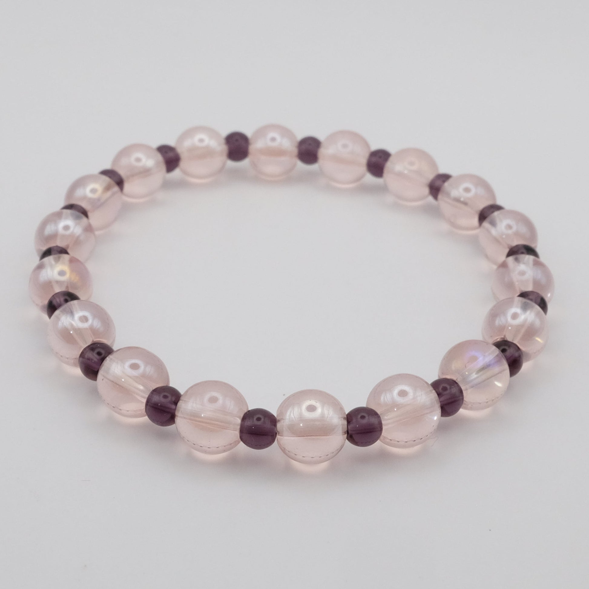 Beaded bracelet with pink and purple beads on a light gray background