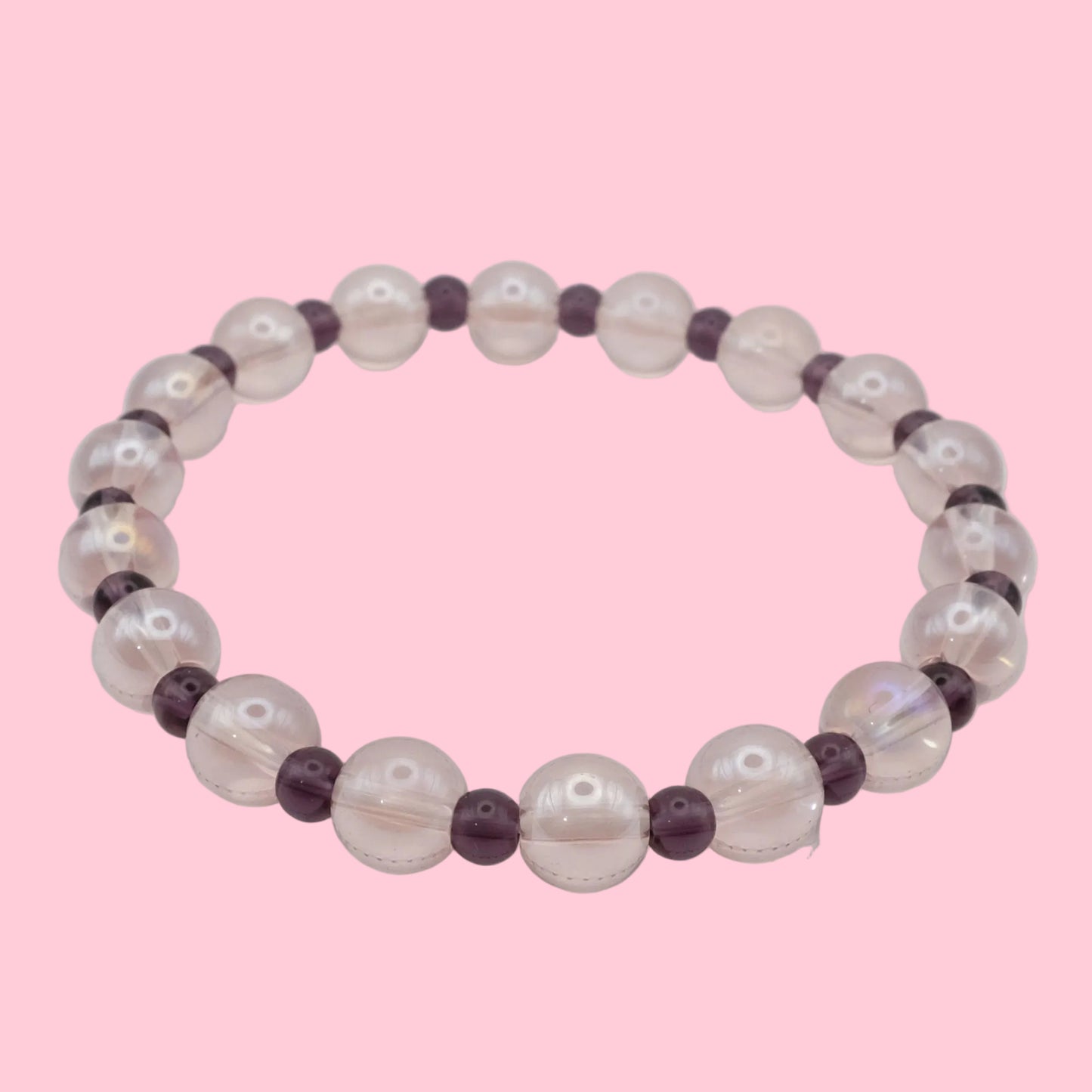 An elastic beaded bracelet composed of translucent light pink 8mm glass beads and deep purple 4mm glass beads, shown on a white background.