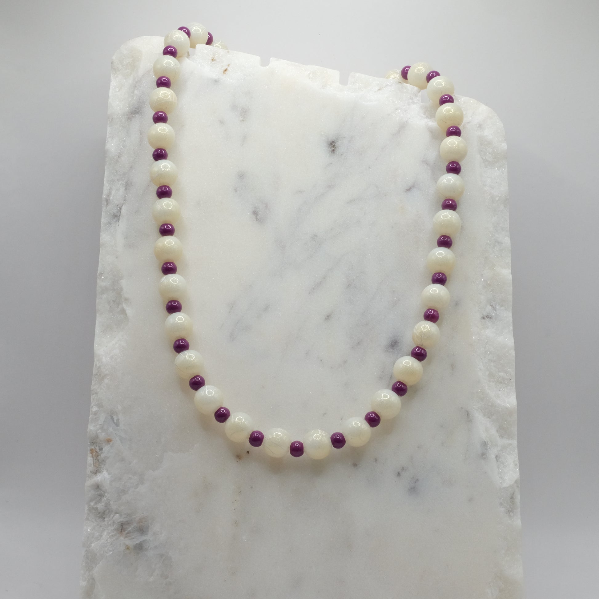 Necklace with white and purple beads on a marble surface