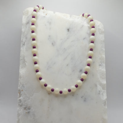 Necklace with white and purple beads on a marble surface