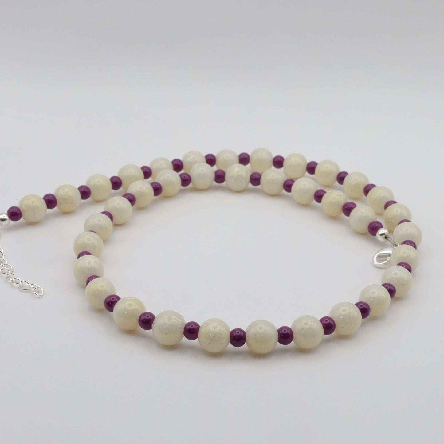 A handmade beaded necklace composed of alternating 8mm metallic cream glass beads and 4mm plum glass beads, shown on a white background.