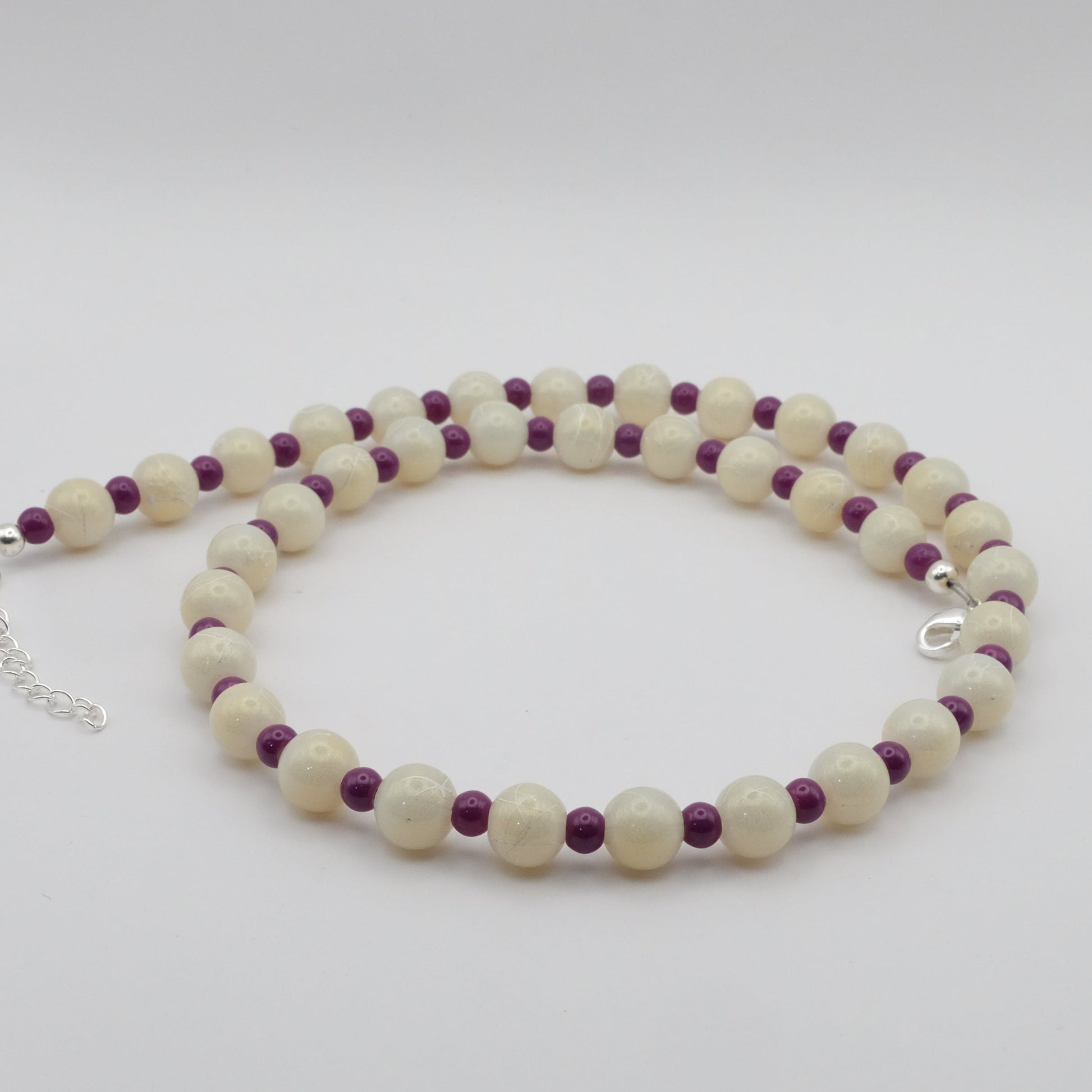 A handmade beaded necklace composed of alternating 8mm metallic cream glass beads and 4mm plum glass beads, shown on a white background.