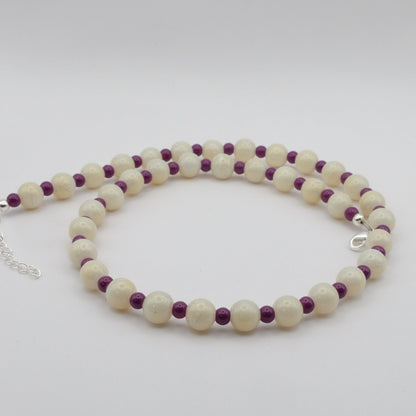 A handmade beaded necklace composed of alternating 8mm metallic cream glass beads and 4mm plum glass beads, shown on a white background.