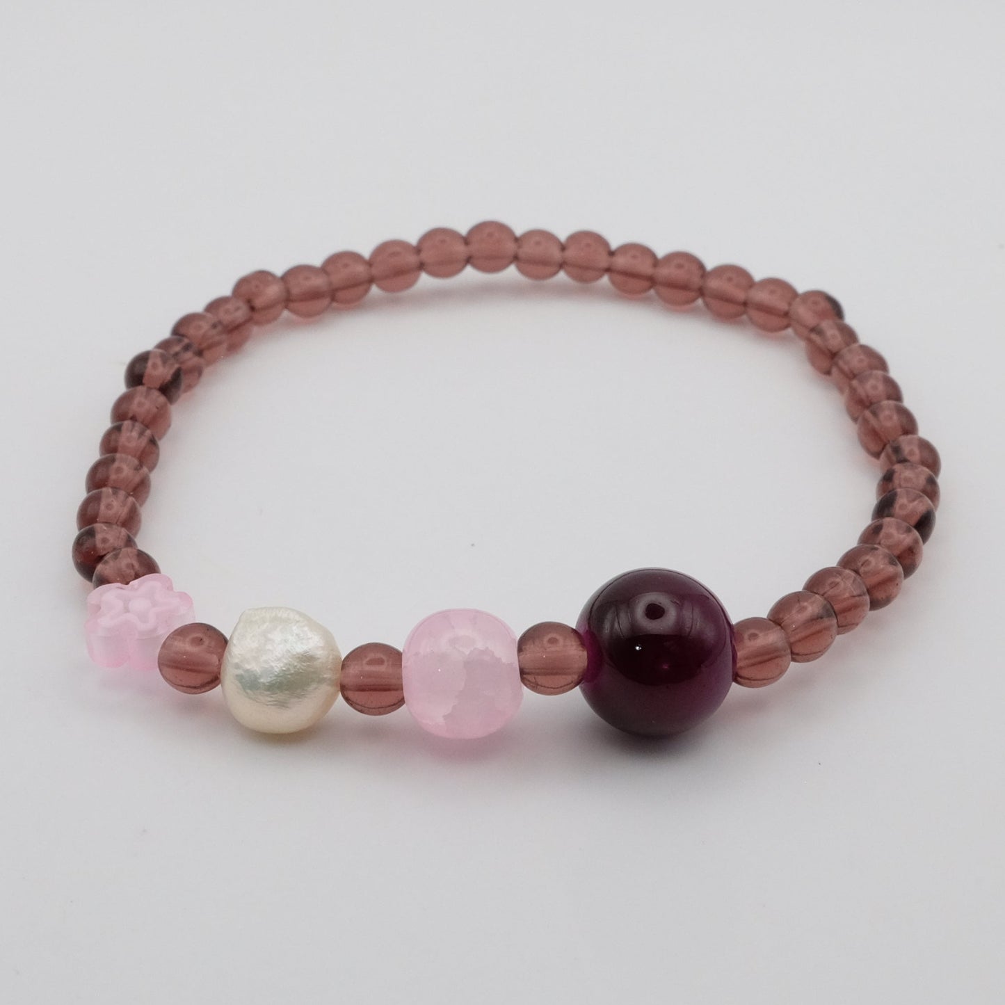 Beaded bracelet with pink, white, and purple beads on a light gray background