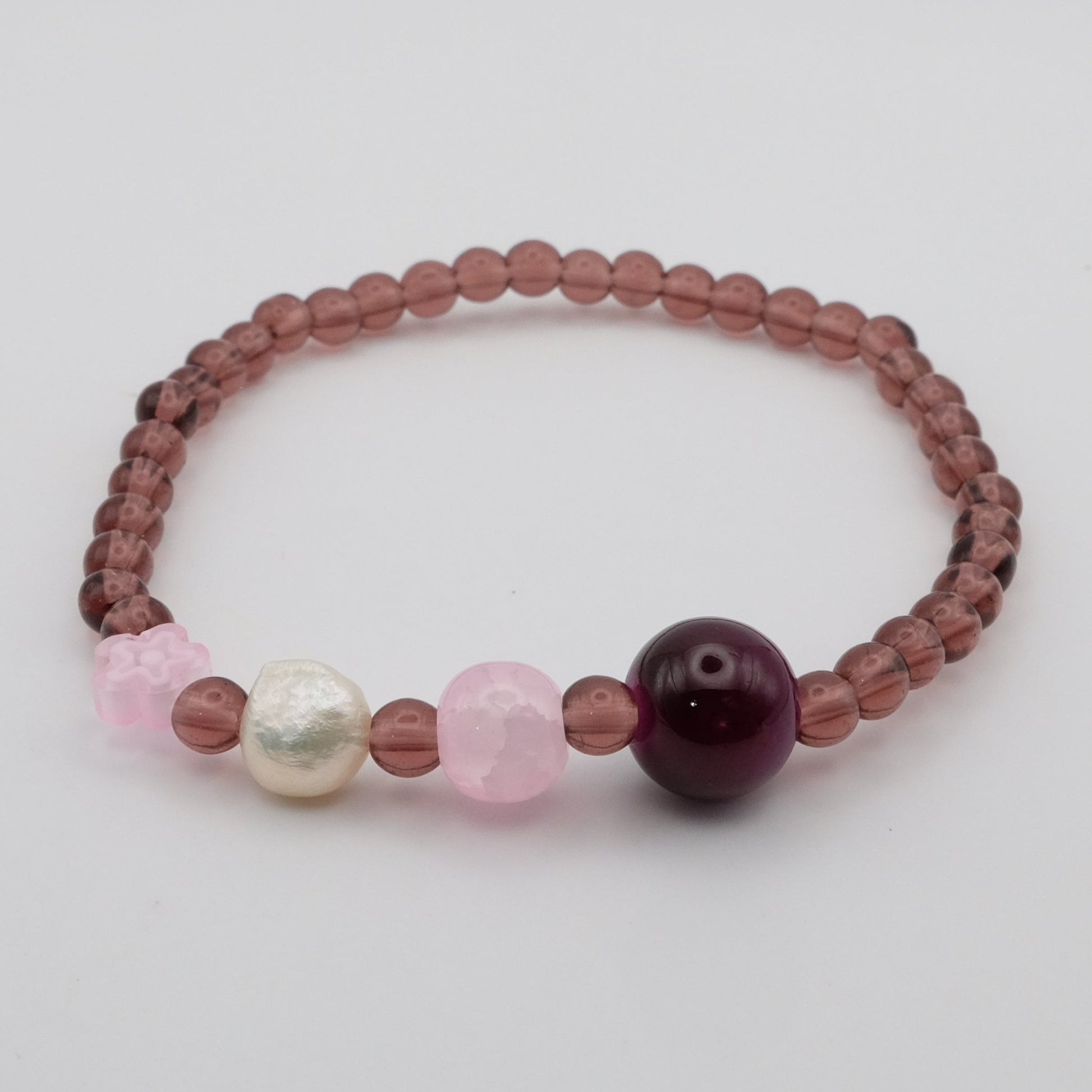 Beaded bracelet with pink, white, and purple beads on a light gray background