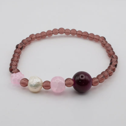 Beaded bracelet with pink, white, and purple beads on a light gray background