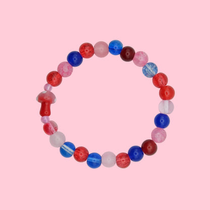 An elastic beaded bracelet composed of 8mm glass beads in red, pink and blue tones - featuring a blown glass toadstool bead, shown on a white background.
