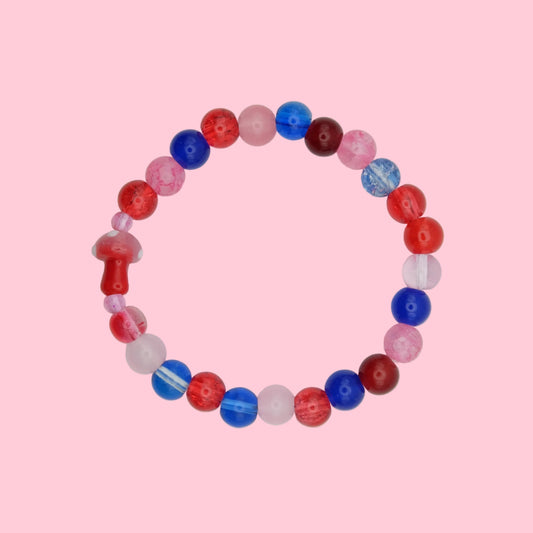 An elastic beaded bracelet composed of 8mm glass beads in red, pink and blue tones - featuring a blown glass toadstool bead, shown on a white background.