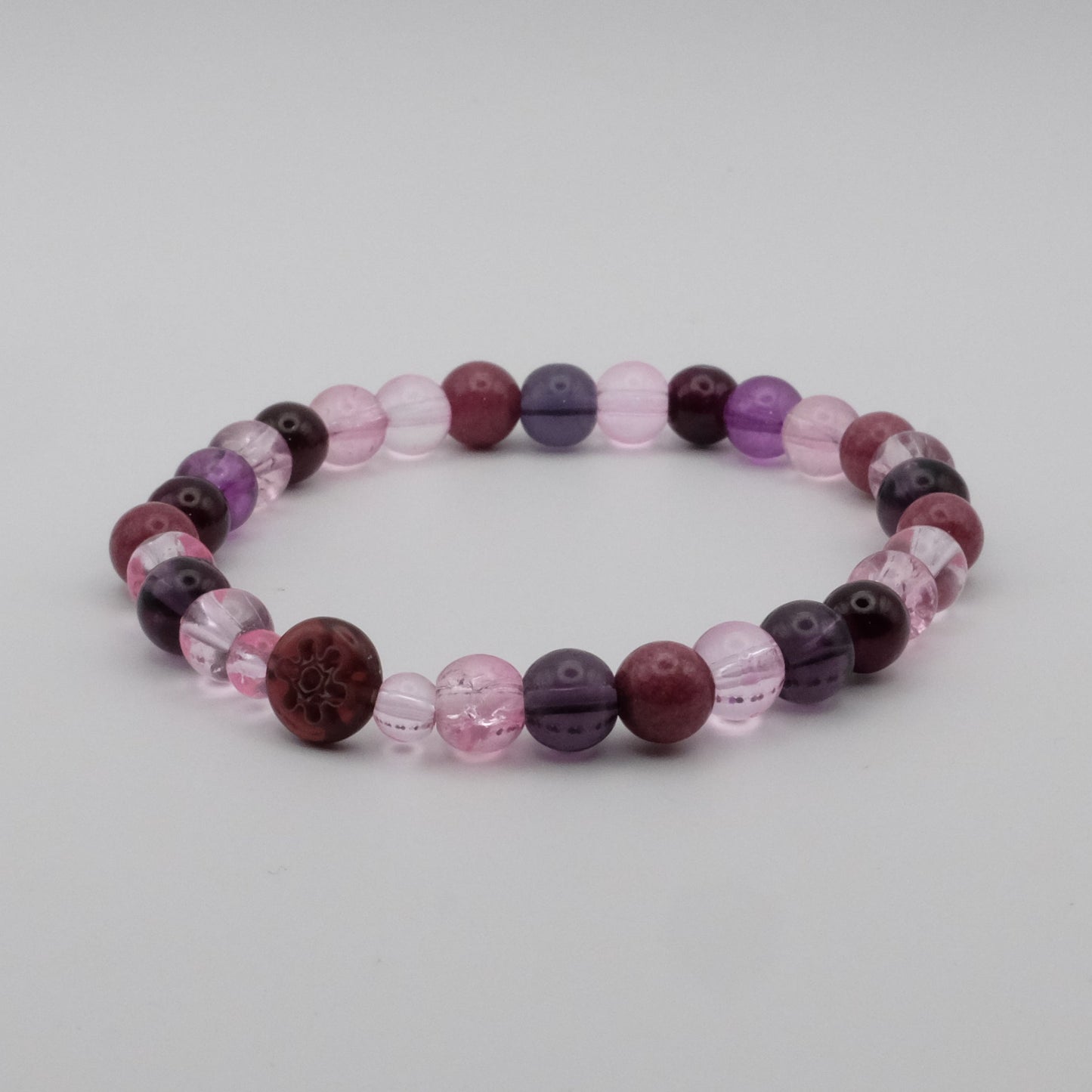 Beaded bracelet with purple and pink beads on a light gray background