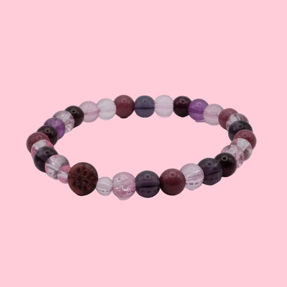An elastic beaded bracelet composed of 6mm blush pink, plum, mauve and deep burgundy beads, featuring a mix of translucent, frosted and marbled finishes with a burgundy floral accent bead, shown on a clean white background.