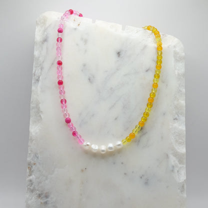 Necklace with pink and yellow beads on a marble surface