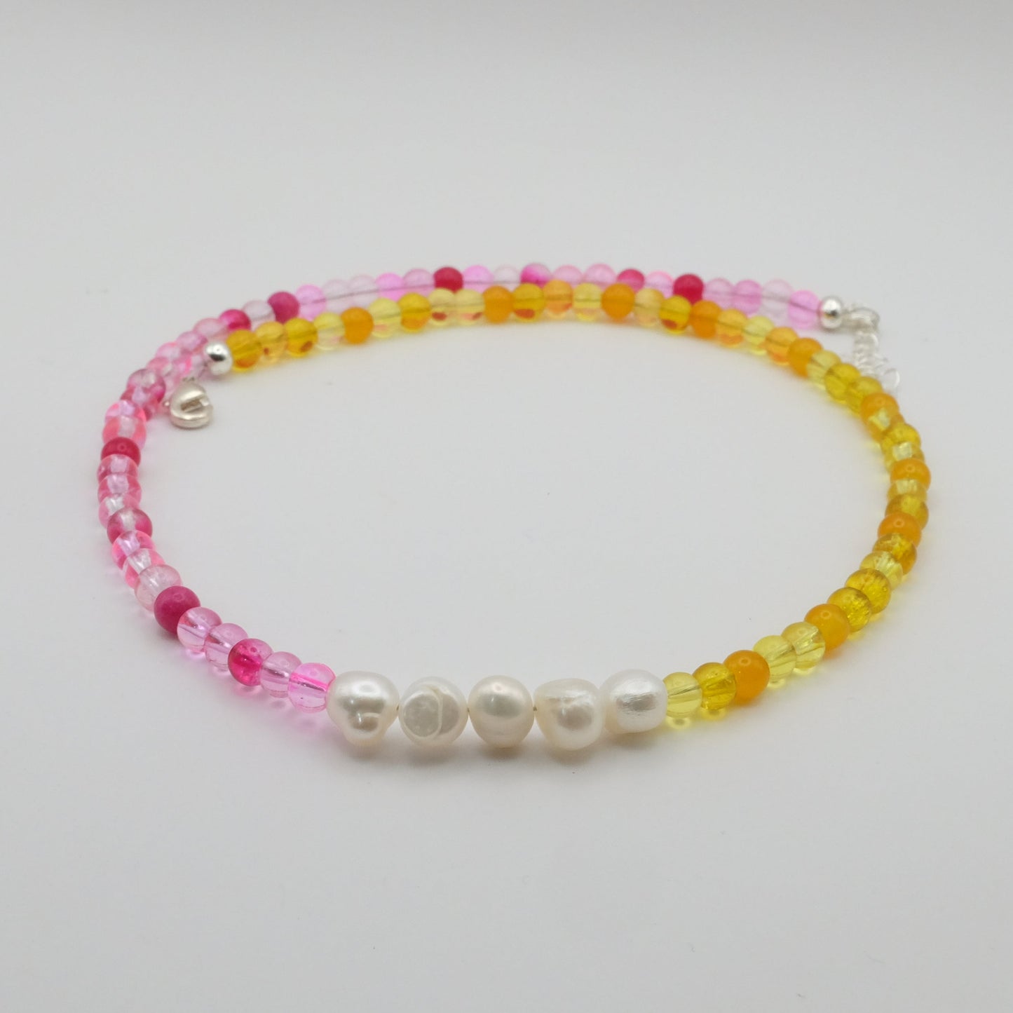 Beaded bracelet with pink, yellow, and white beads on a light gray background