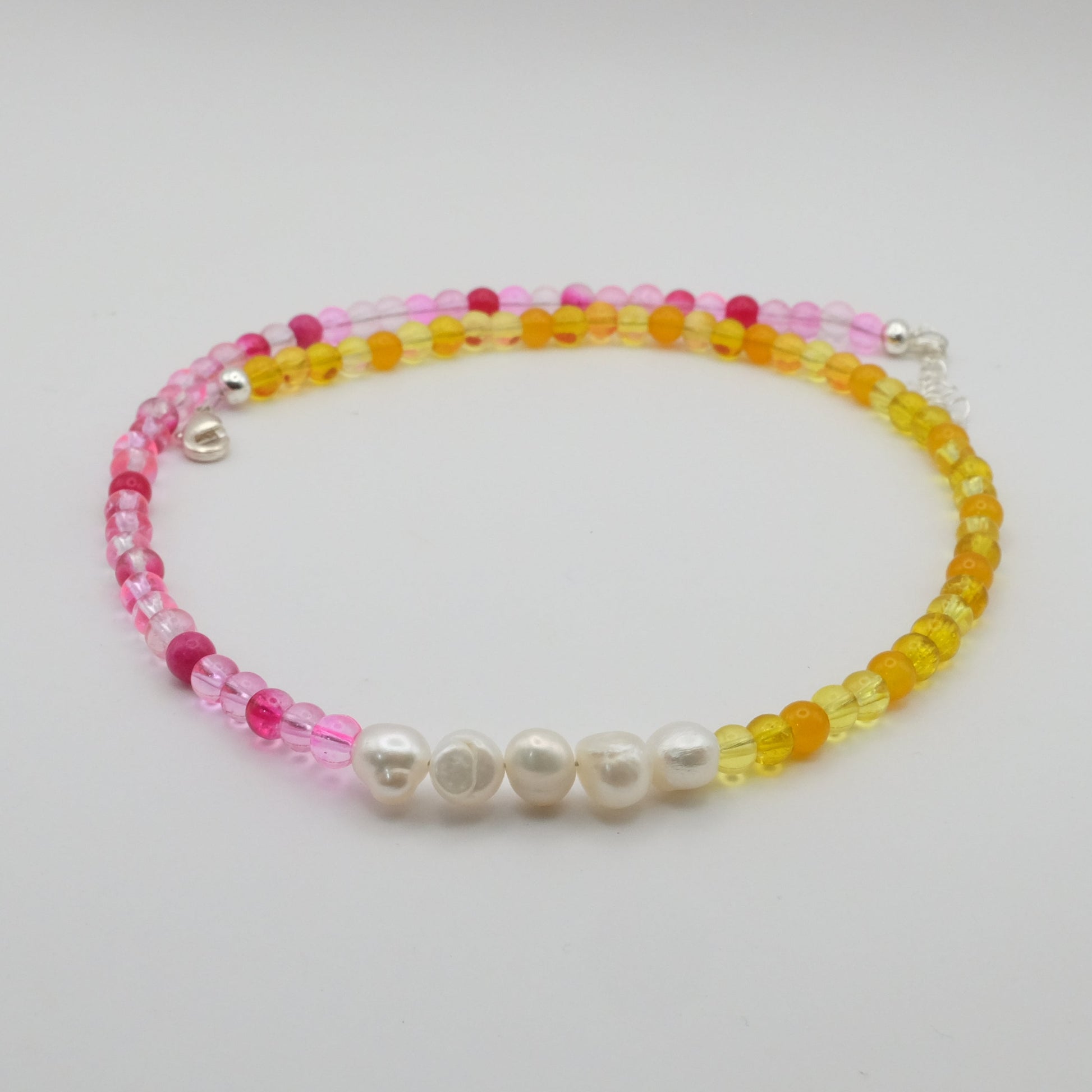 Beaded bracelet with pink, yellow, and white beads on a light gray background
