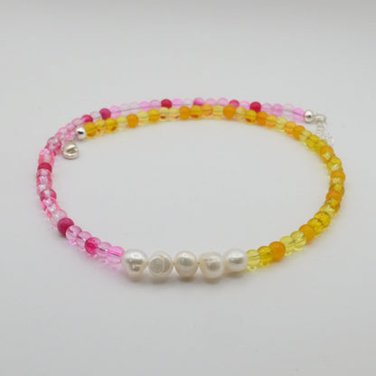 Beaded bracelet with pink, yellow, and white beads on a light gray background