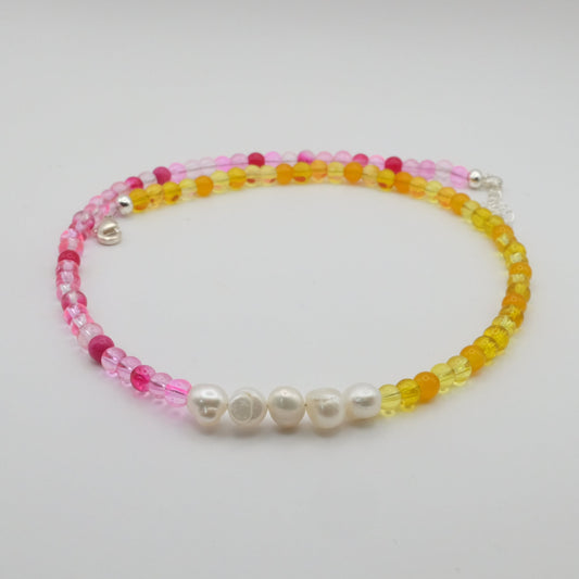 Beaded bracelet with pink, yellow, and white beads on a light gray background