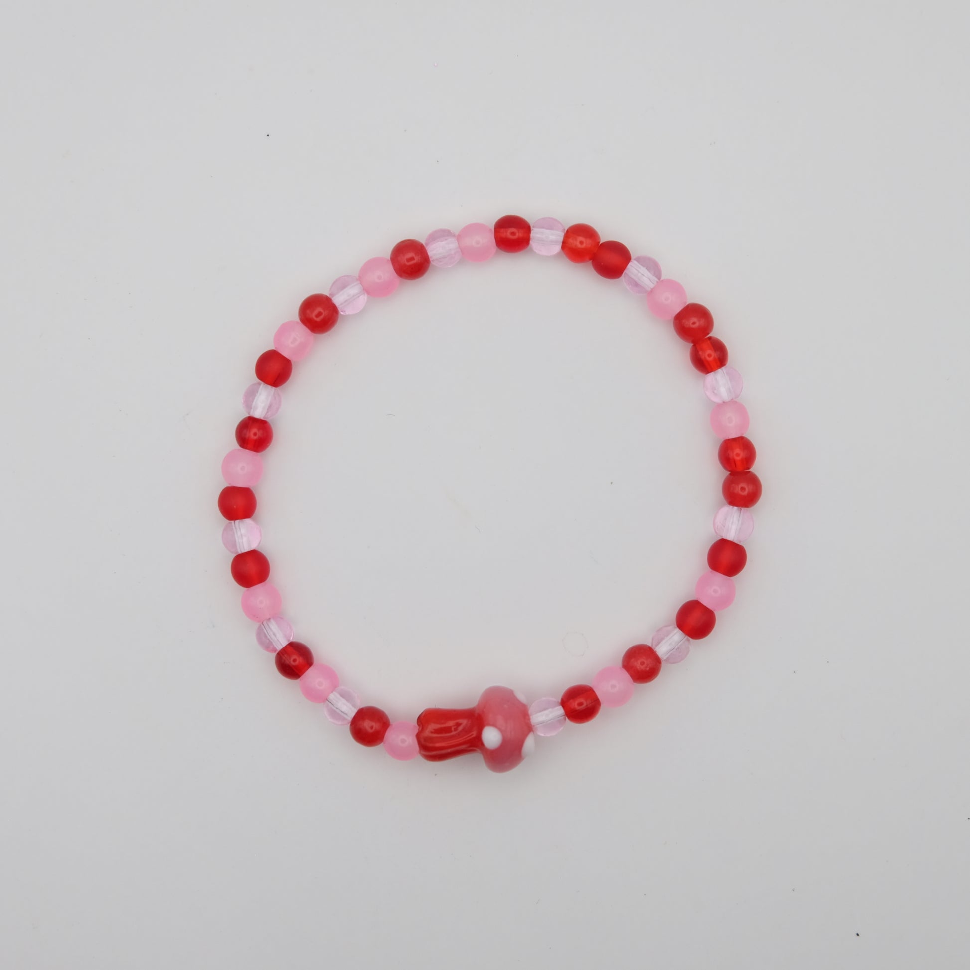 Beaded bracelet with red and pink beads on a light gray background
