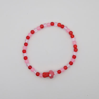 Beaded bracelet with red and pink beads on a light gray background