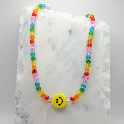 Rainbow beaded necklace with a ceramic smiley face bead  on a marble surface