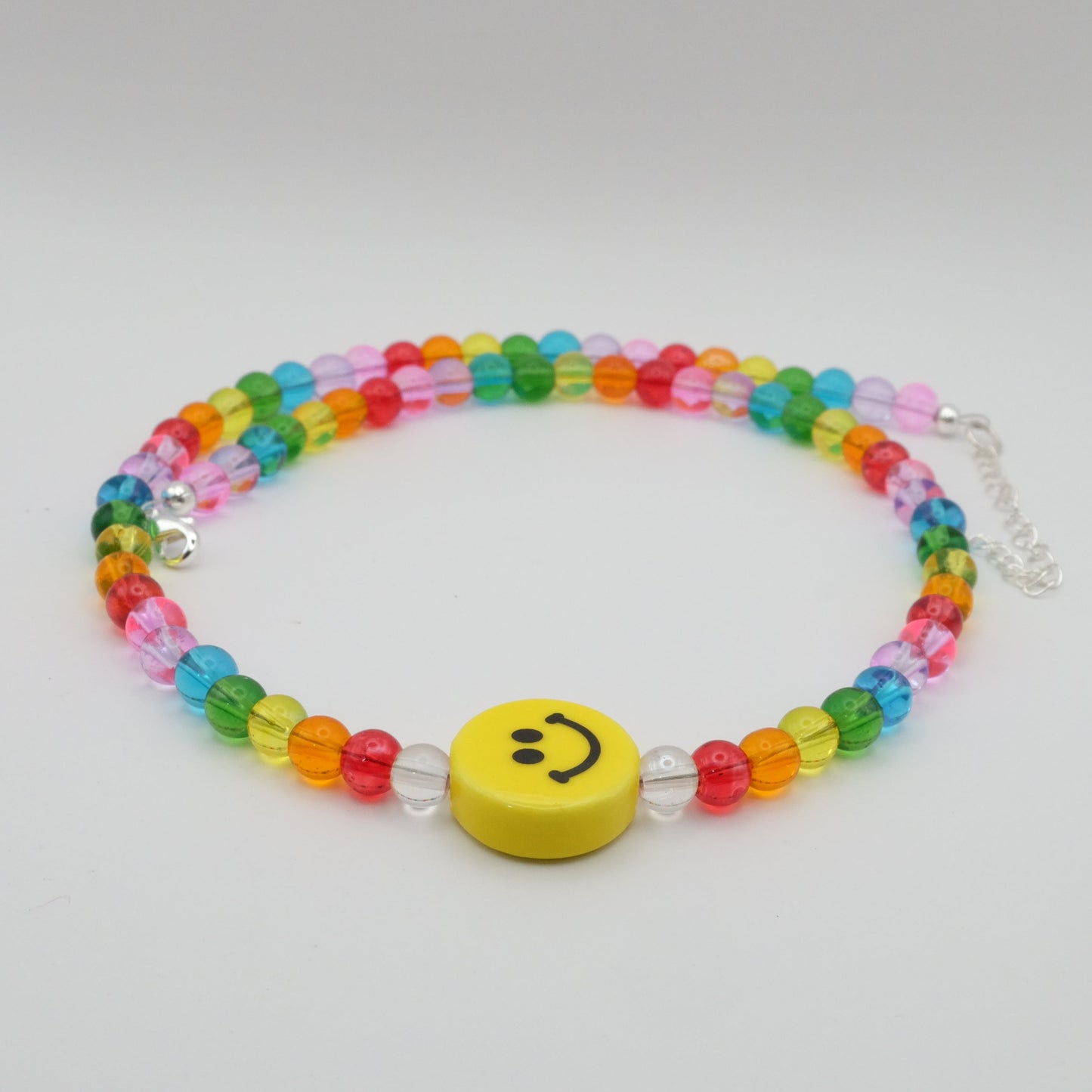 Colorful beaded necklace with a smiley face charm on a light gray background